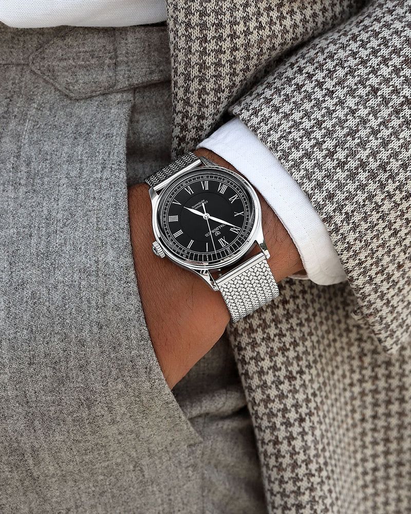 A round Automatic mens watch in Rhodium-plated 316L stainless from Waldor & Co. with black double-layered dial in copper. Curved mineral glass with anti-reflective coating. Miyota 9093 movement. Mesh strap. The model is Continual 39 Amalfi.