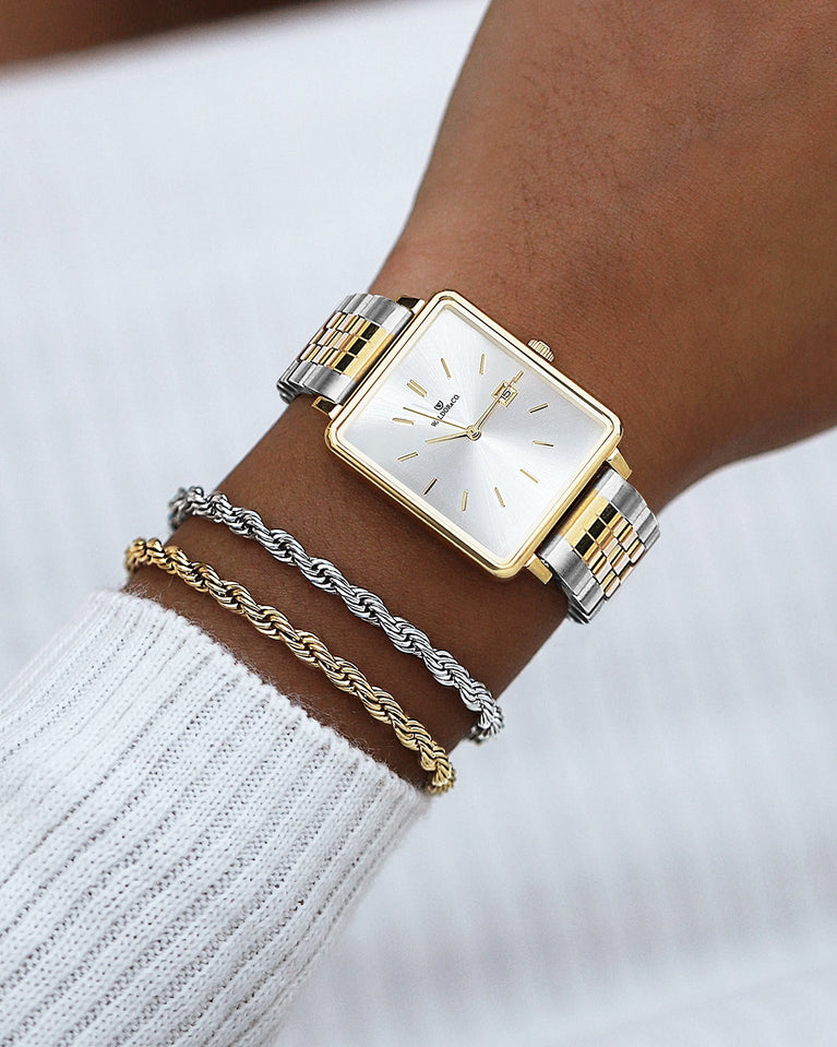  A square womens watch in silver and 14k gold from Waldor & Co. with silver sunray dial and a second hand. Seiko movement. The model is Delight 32 Chelsea 28x32mm.