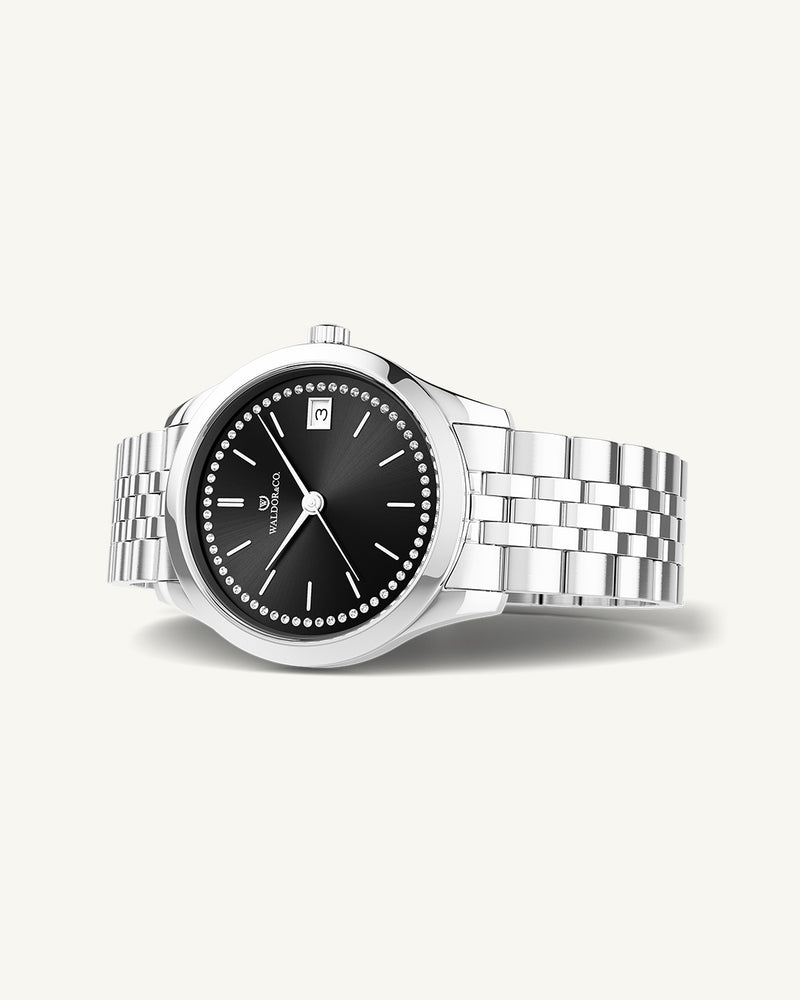 A round womens watch in Rhodium-plated 316L stainless steel from Waldor & Co. with black sunray dial and a second hand. Seiko movement. The model is Imperial 36 Roma 36mm