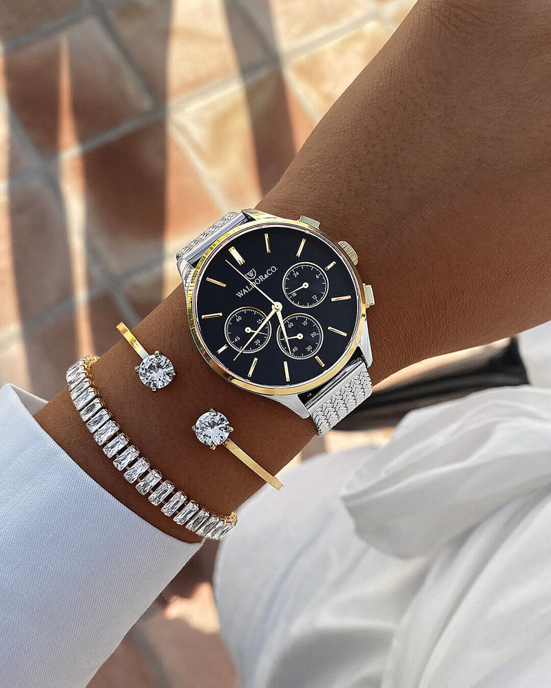 A round womens watch in14k gold-plated 316L stainless steel from Waldor & Co. with black dial  and a second hand. Seiko movement. The model is Epoch 36 Formentera 36mm.
