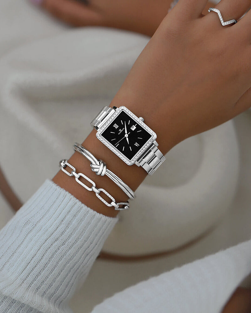 A square womens watch in silver with stones from WALDOR & CO. with black sunray dial and a second hand. Seiko VJ22 movement. The model is Delight 32 Mayfair 28x32mm. 