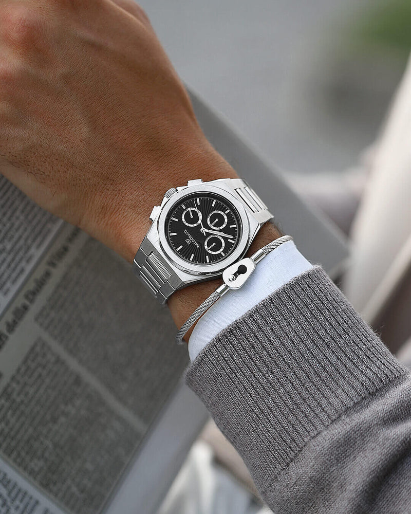 A round mens watch in rhodium-plated silver from Waldor & Co. with black sunray dial and luminous hands. Seiko movement. The model is Inceptive 40 Azores.
