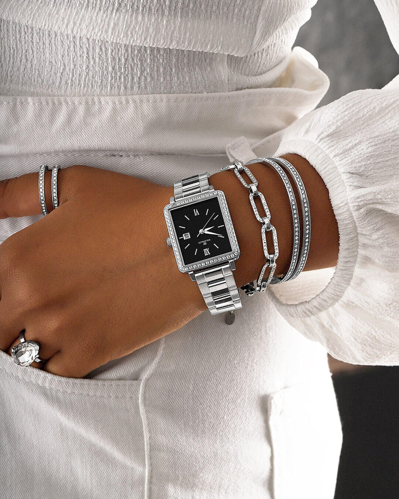 A square womens watch in silver with stones from WALDOR & CO. with black sunray dial and a second hand. Seiko VJ22 movement. The model is Delight 32 Mayfair 28x32mm. 