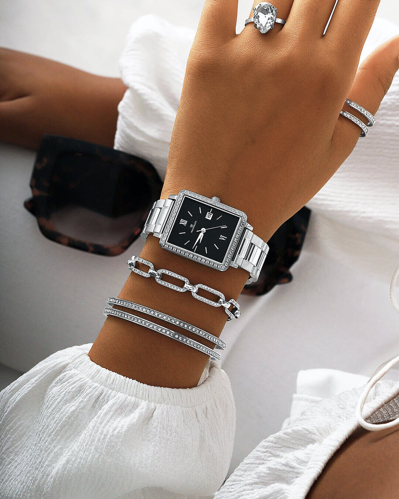 A square womens watch in silver with stones from WALDOR & CO. with black sunray dial and a second hand. Seiko VJ22 movement. The model is Delight 32 Mayfair 28x32mm. 